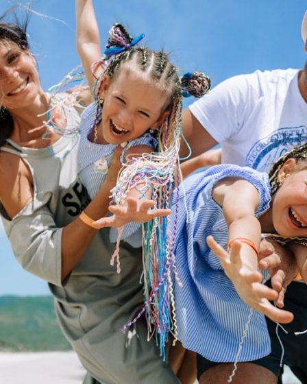 Happy family taking a joyful selfie on a sunny beach vacation, blue sky and summer vibes.