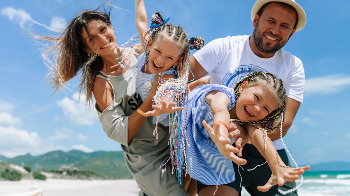 Happy family taking a joyful selfie on a sunny beach vacation, blue sky and summer vibes.